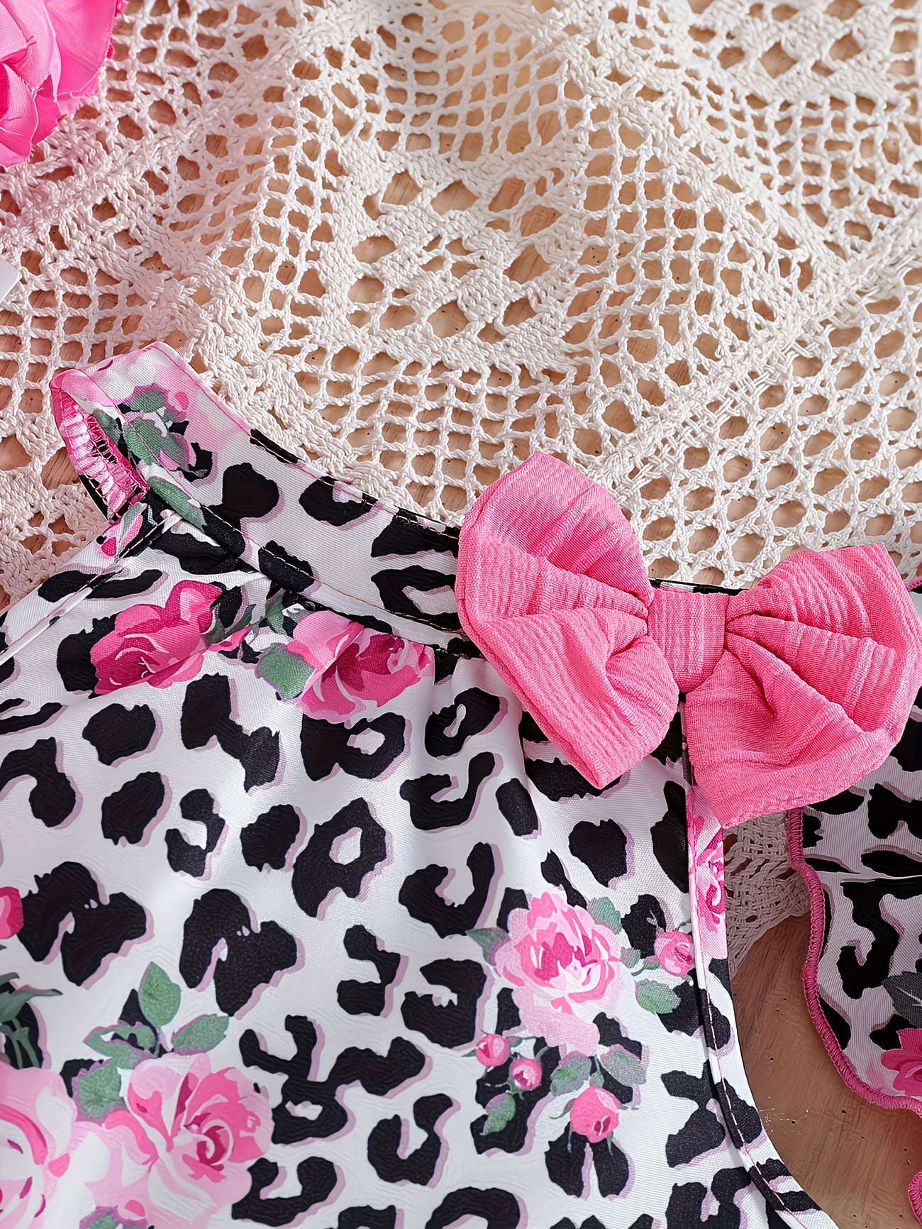 Primer plano del detalle del chaleco con estampado de leopardo, rosas rosadas y un moño rosa en el cuello, parte del conjunto para niña de Soñando en Azul.