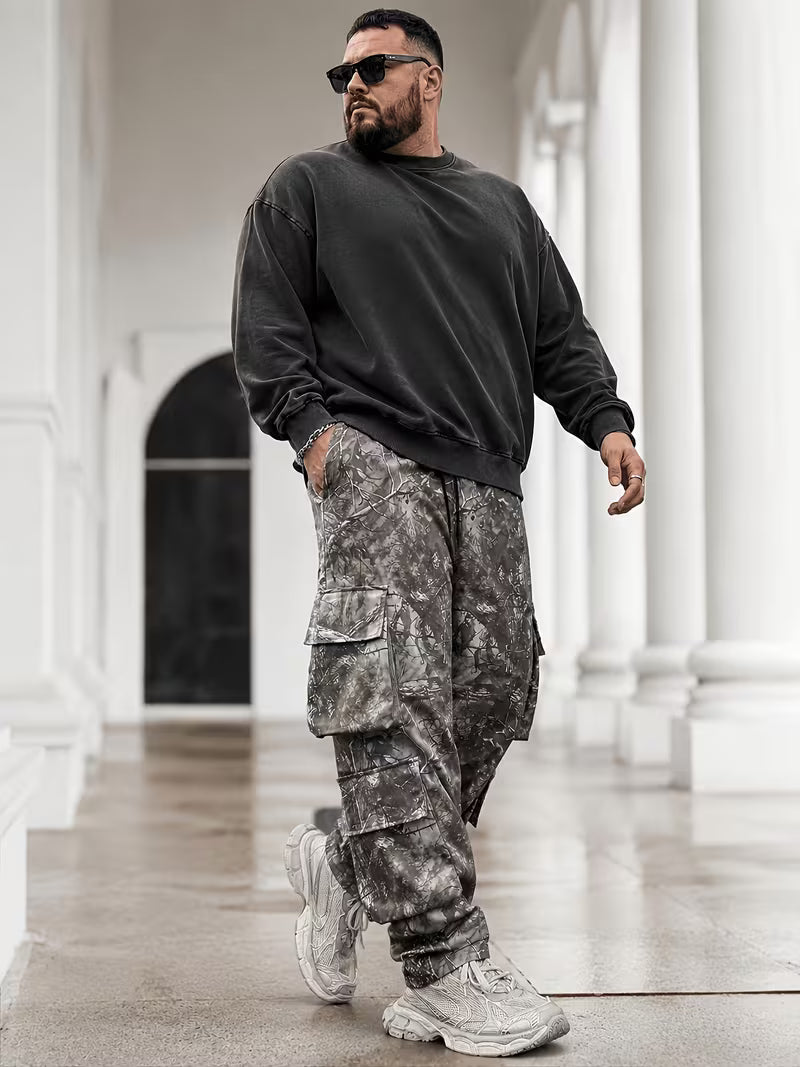 Modelo con pantalón cargo de camuflaje gris para hombre en tallas grandes, combinado con sudadera oscura.

