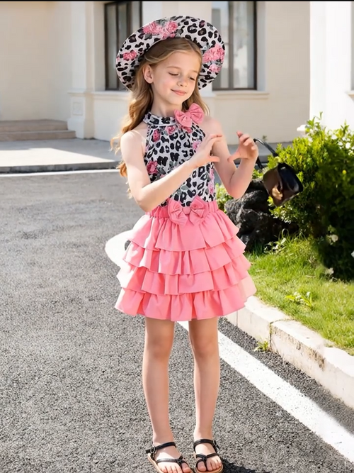 Niña posando con conjunto de moda urbana infantil que incluye blusa de leopardo con rosas, falda rosa con capas y moño, y sombrero floral a juego, de Soñando en Azul.